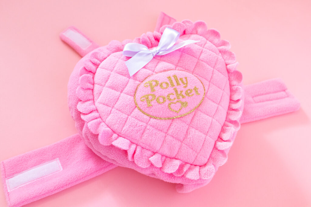 Close-up of Polly Pocket dog costume. It's made from pink fleece and is a heart shape with quilting and scallops around the edges.