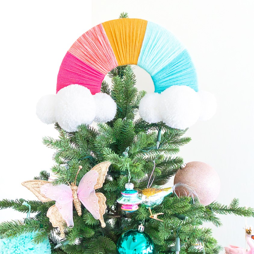 Rainbow Christmas tree topper made from colored yarn and giant white pom poms.